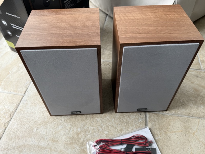 the speaker pair with a bagged set of speaker cables resting alongside