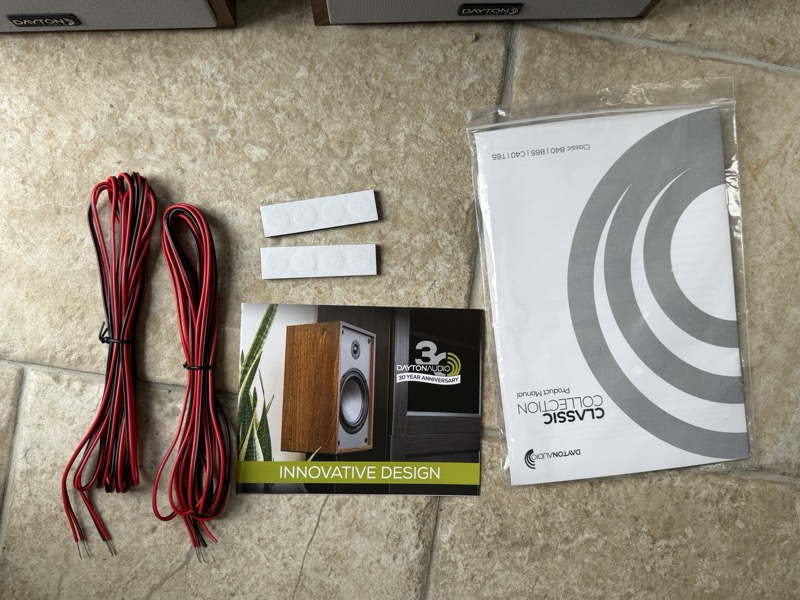 the full accessory set: speaker wire, rubber feet, the manual, and the 30th-anniversary brochure