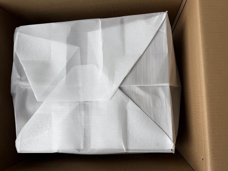 the subwoofer wrapped in its protective white packaging sleeve inside the box