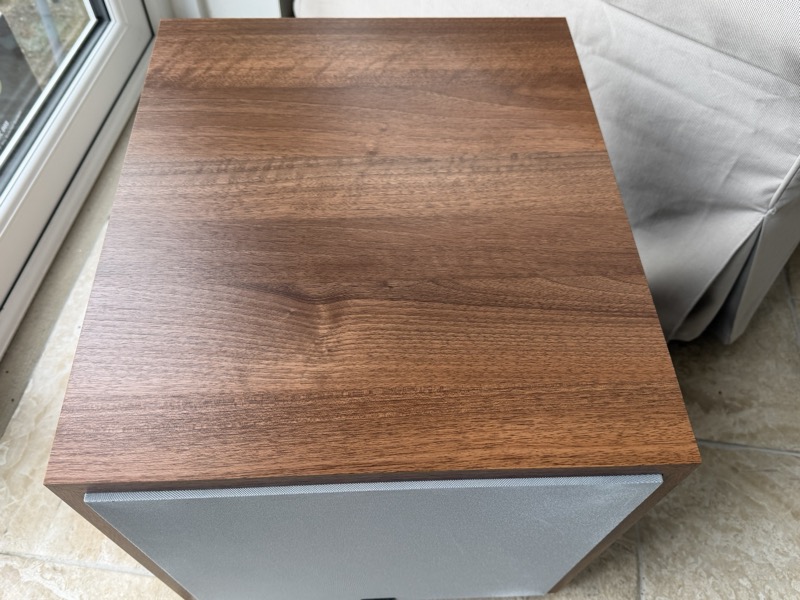 the assembled subwoofer, showing the wood-finish top panel and grille edge