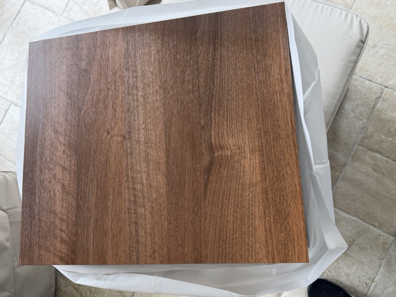 the top wood-finish panel, still wrapped in plastic before fitting