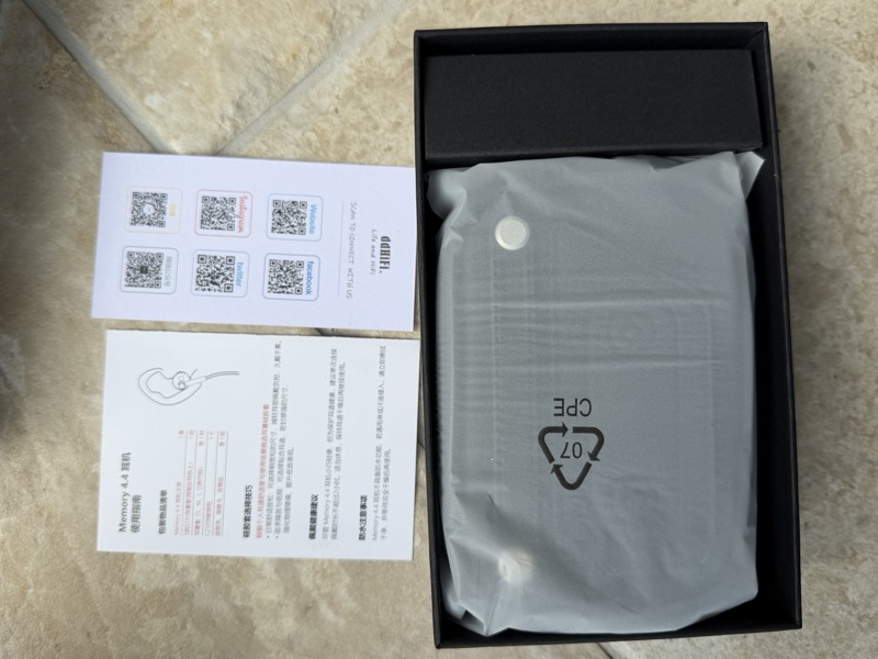 the manual and QR code card, sitting above the wrapped carrying case inside the box