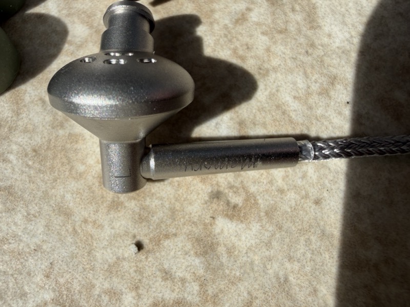 a single earpiece, showing the “Memory” branding engraved into the metal barrel where the fixed cable enters the shell