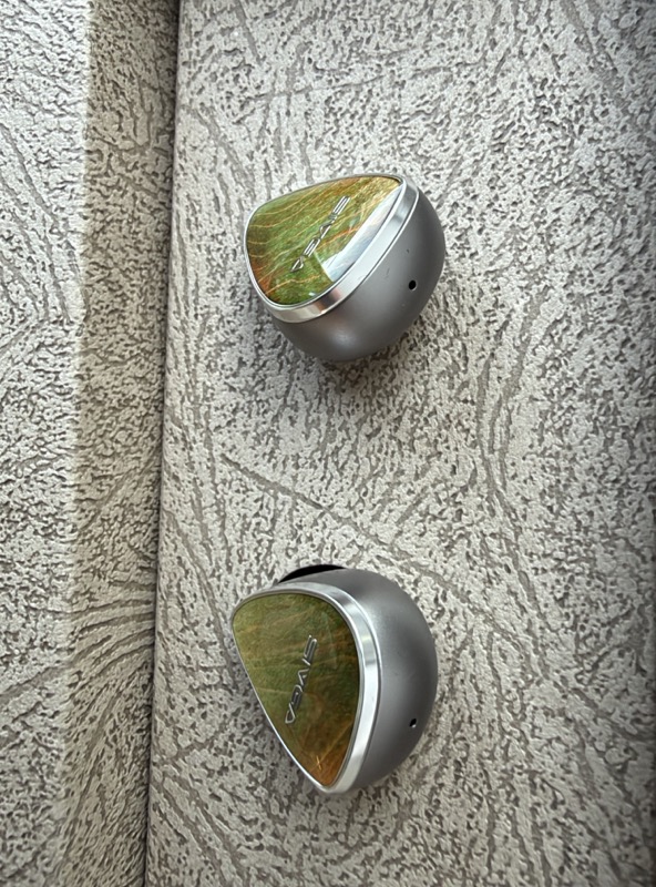 the earpieces showing the wood faceplates against the alloy shells