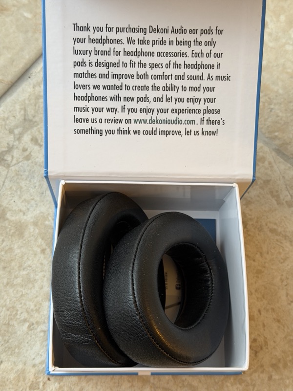 open choice leather box with dekoni thank-you note printed inside the lid and the pads in the tray below