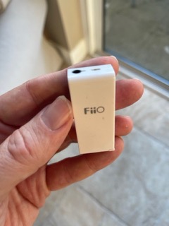 an early keyring-sized FiiO headphone amplifier held in one hand for scale