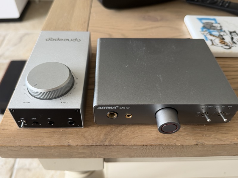 the small silver Gigas1 beside the much larger Aiyima DAC-A7 on a desk