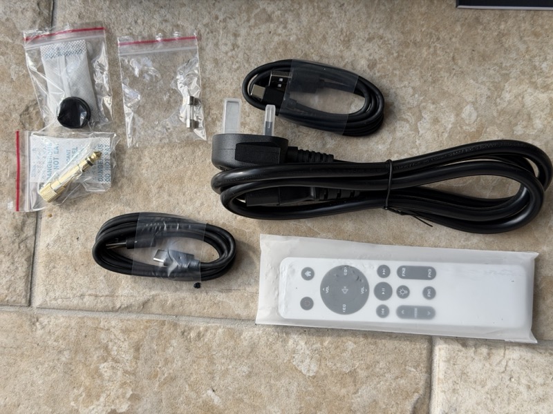 accessories laid out: mains cable, two usb cables, 6.35mm adapter, spare fuse, xlr dust plug and the remote