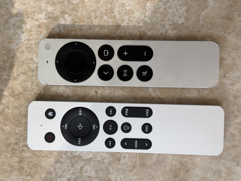 the fiio k17 r2r remote laid next to an apple tv remote for size comparison