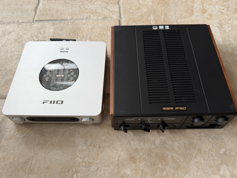 the fiio k13 r2r next to the much larger k17 r2r, with the k13’s resistor array visible through a circular window