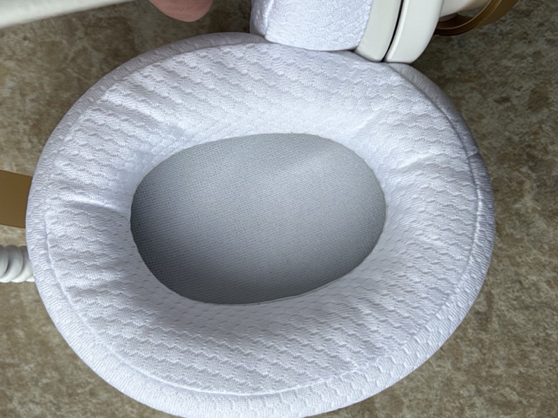 the stock white knit earpad seen face-on, with the grey acoustic scrim over the driver opening
