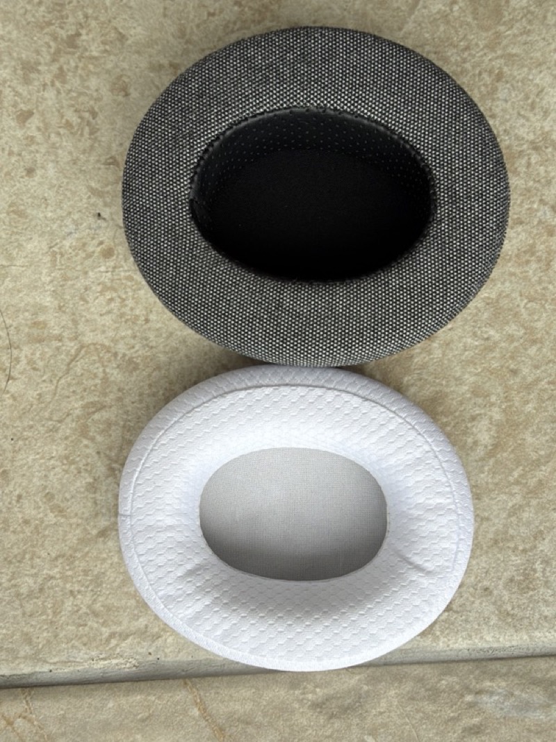 the grey third-party replacement earpad above the white stock gm01 pro pad